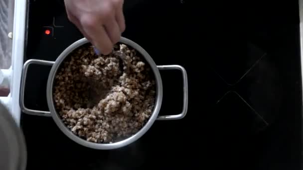 Mano Mescolare il grano saraceno in una casseruola . — Video Stock