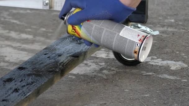 Schwarze Sprühfarbe in der Hand bemalt eine Holz- und Stahlkonstruktion. Zeitlupe. — Stockvideo