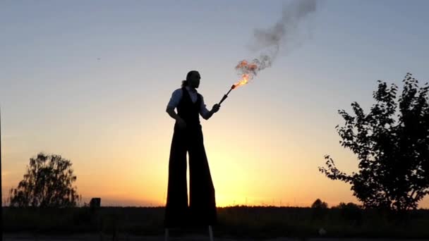 Günbatımında harika gösteri. Sirk Stilts üzerinde yangın çıkar ağzındaki baklayı. Ağır çekim. — Stok video