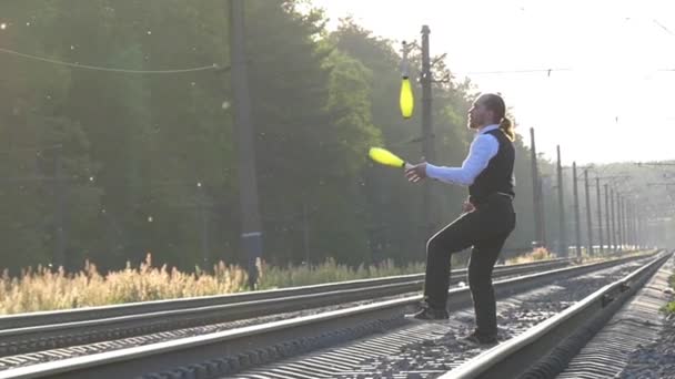 Guy žonglování na koleje. Zpomalený pohyb. Západ slunce. Vyvažování na železnici. — Stock video