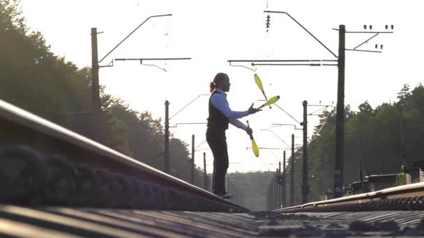Парень жонглирует железнодорожными путями. Медленное движение. Закат. Балансировка на железной дороге . — стоковое видео