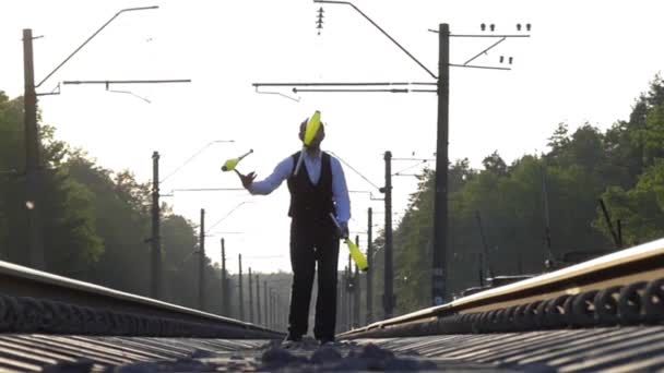 Guy jonglering på järnvägsspåren. Slow Motion. Solnedgång. Balansera på järnvägen. — Stockvideo