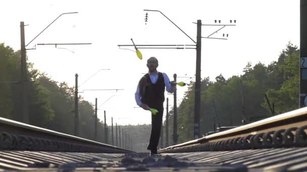 Le gars qui jongle sur les rails. Au ralenti. Coucher de soleil. Équilibre sur le chemin de fer . — Video