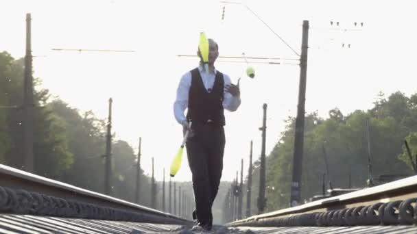 Guy jonglering på järnvägsspåren. Slow Motion. Solnedgång. Balansera på järnvägen. — Stockvideo