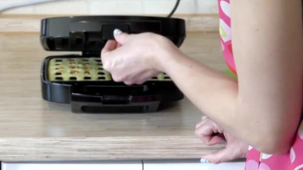 Дівчина готується бельгійські вафлі в спеціальних вафельниці. — стокове відео