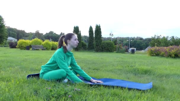Спортивная девушка делает упражнения в парке. Сидящая позиция . — стоковое видео