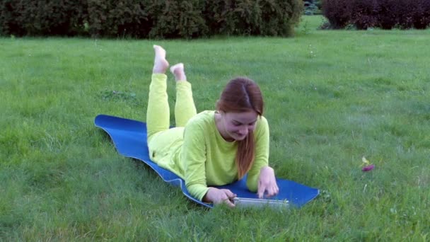 Sporty Girl Après le Yoga, Allongé sur l'estomac et en utilisant sa tablette. Souriant . — Video