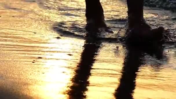在日落时，在海洋海岸上缓慢运动中行走的双腿的剪影. — 图库视频影像