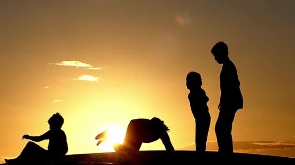 Щасливі діти, стрибки на батуті під час заходу сонця в уповільненому Русі. — стокове відео