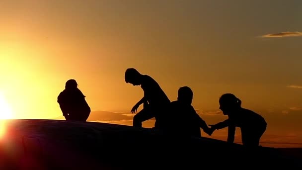 Crianças felizes pulando em um trampolim durante o pôr do sol em câmera lenta . — Vídeo de Stock