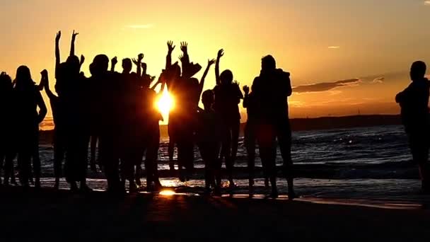 Las personas son fotografiadas en un salto al atardecer cerca del mar. Moción lenta . — Vídeo de stock