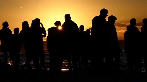Silhouette Les gens au coucher du soleil près de la mer. Mouvement lent . — Video