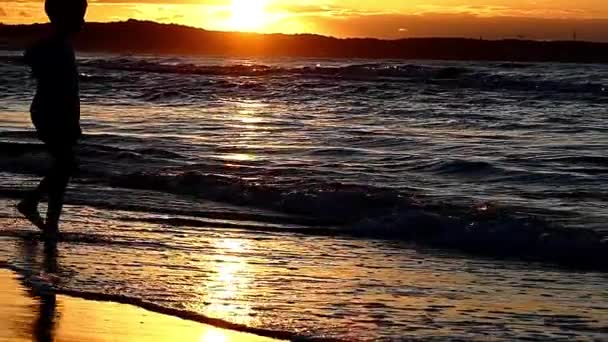 Petits garçons marchant dans les vagues pendant le coucher du soleil. Mouvement lent . — Video