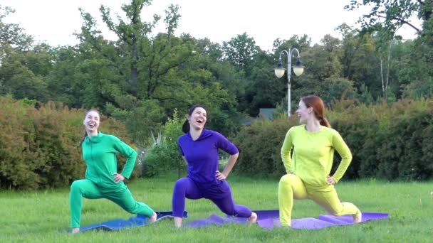 Yoga nel parco. Tre ragazze in sport indossare gambe allungate . — Video Stock