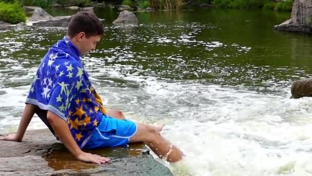 Un jeune homme mouille ses pieds dans l'eau tourbillonnante. Mouvement lent . — Video