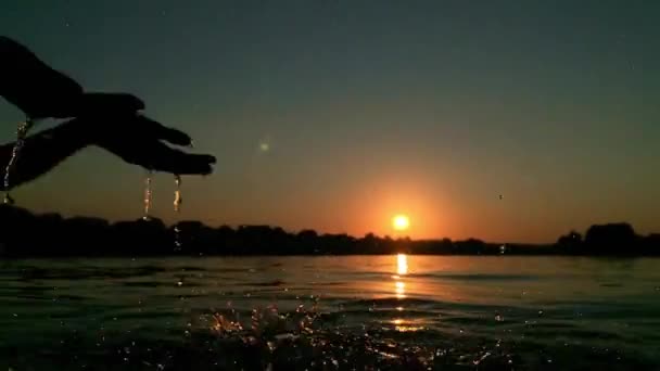 Hand erzeugt viel Spritzer bei Sonnenuntergang. — Stockvideo