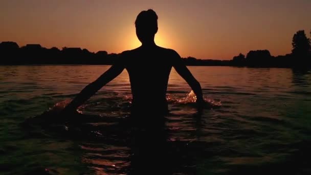 Schönes Mädchen, das bei Sonnenuntergang mit Wasser spielt. — Stockvideo