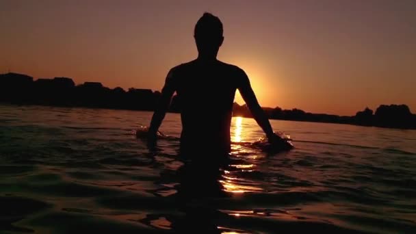 Menina bonita brincando com água ao pôr do sol . — Vídeo de Stock