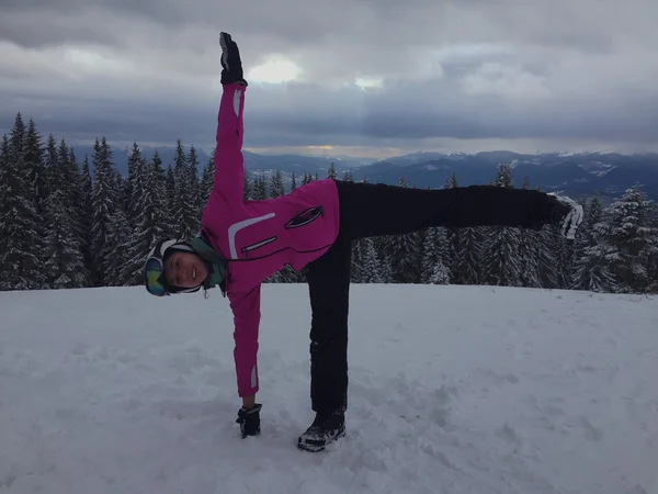 Winter yoga. Girl standing in yoga pose in top of mountain.