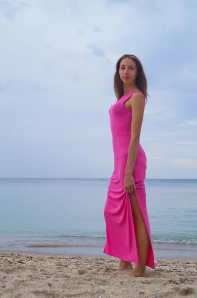 Menina bonita em vestido rosa de pé perto do mar — Fotografia de Stock