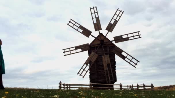 Gamla vindkraftverk i fältet isolera. Flicka som går på gatan nära wind mill. — Stockvideo