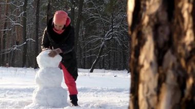 Kızı ormanda kışın kardan adam yapar. Çam çerçeve.