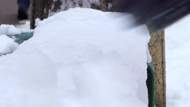 La mano en el guante limpia el banco verde de la nieve durante el clima invernal . — Vídeos de Stock