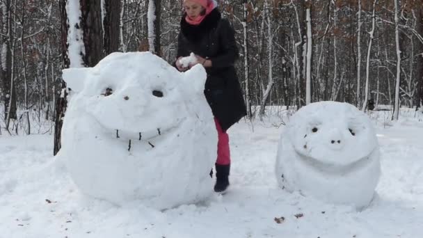 Het meisje eindigt maken een groot hoofd uit de sneeuw. Een grappig figuur. — Stockvideo