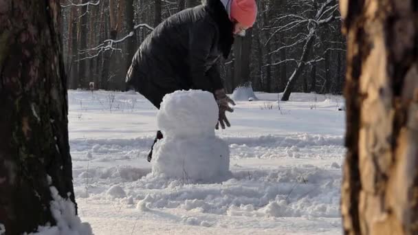 Το κορίτσι κάνει χιονάνθρωπος χειμώνα στο δάσος. Πλαίσιο των πεύκων. — Αρχείο Βίντεο