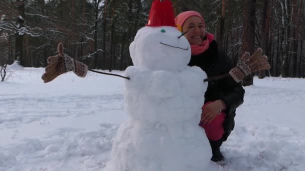 这个女孩完成在冬天森林里堆雪人. — 图库视频影像
