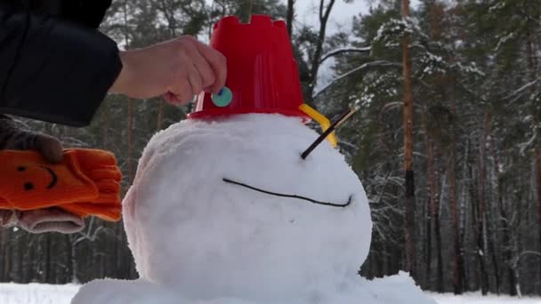 Het meisje klaar bent met het maken van een sneeuwpop in het winter forest. — Stockvideo