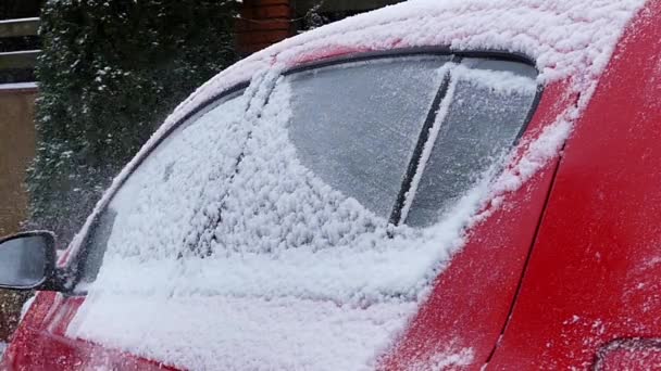 Το κορίτσι καθαρίζει χιόνι για το κόκκινο αυτοκίνητο. Δράση σε αργή κίνηση. — Αρχείο Βίντεο