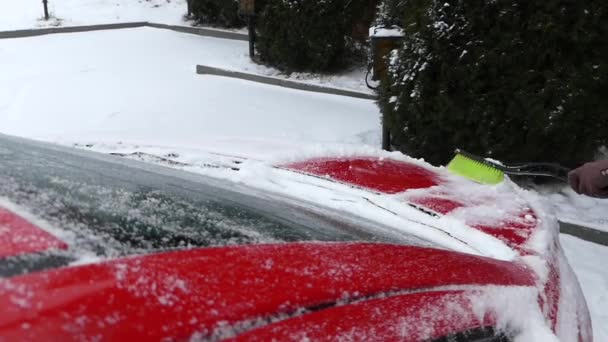 Cepillo verde limpiando nieve en el coche rojo. Acción en tiempo real. Invierno . — Vídeo de stock