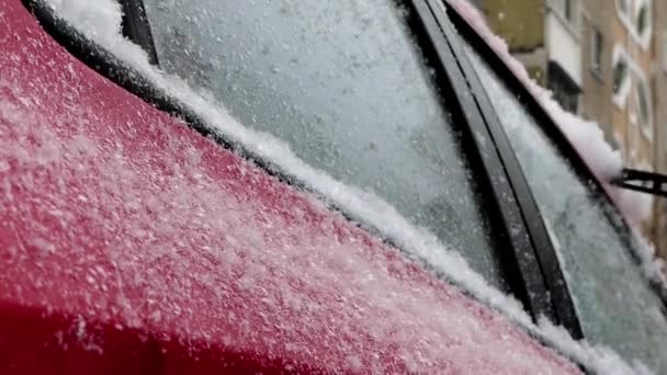 El hombre limpia la nieve en el coche rojo . — Vídeos de Stock