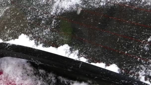 L'homme nettoie la neige sur la voiture rouge . — Video