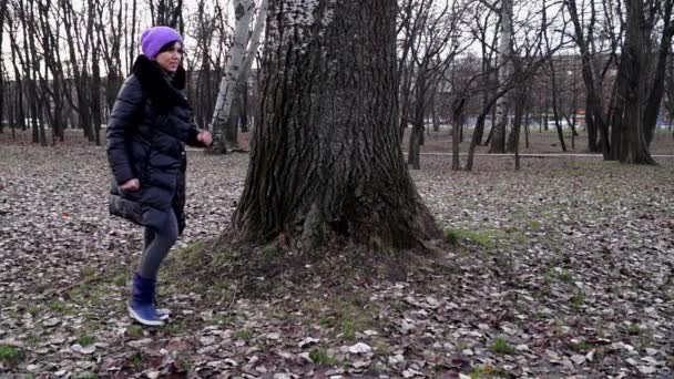 Dívka chodí kolem stromu v parku. — Stock video