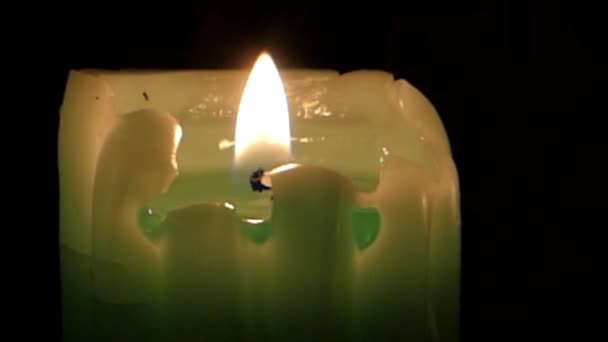 Das Feuer einer grünen Kerze im Dunkeln. windig in der Kirche. — Stockvideo