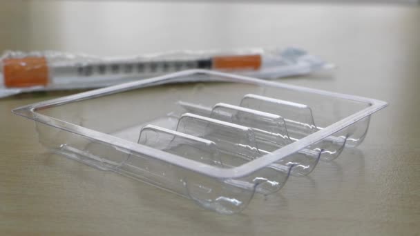 Lege verpakkingen voor stimulatiedosis op de voorgrond in nadruk en syringe onscherp. — Stockvideo