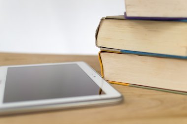 Bir tablet yanındaki ciltli kitaplar