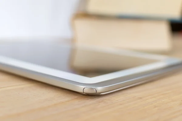 Tablet met boeken in de achtergrond en weerspiegeld in het scherm Stockfoto