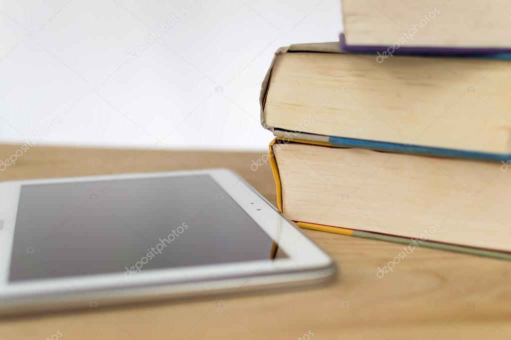 Hardcover books next to a tablet