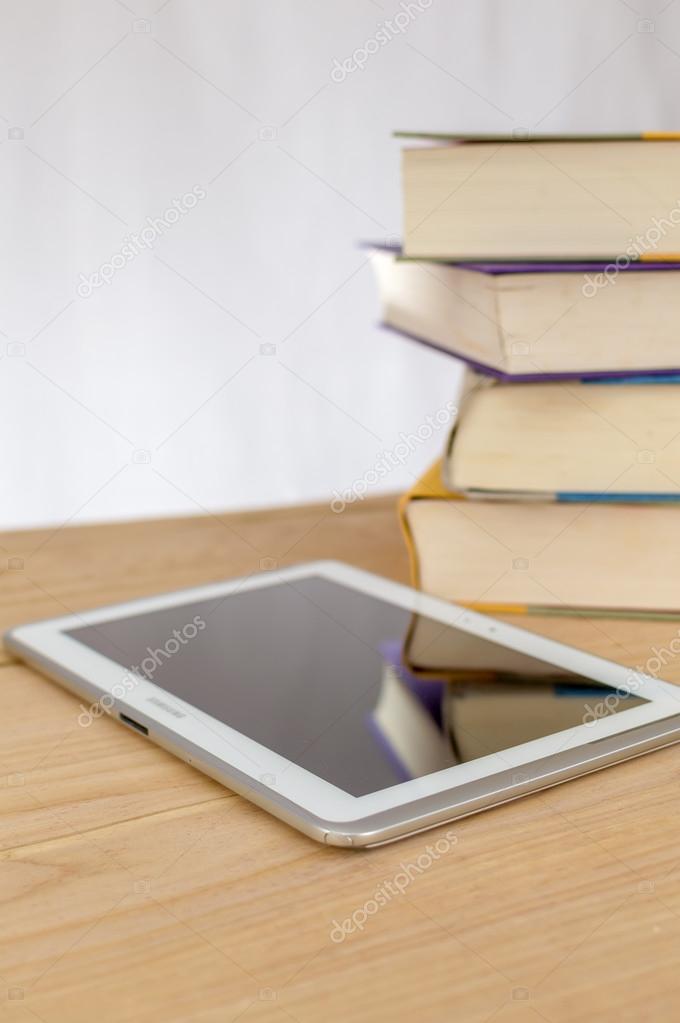 A stack of books next to an electronic reader