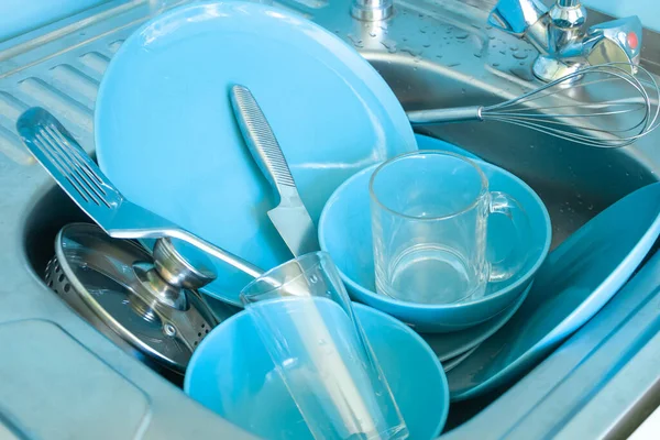 dishes in the sink close up, blue plates, stainless steel knife, bowls, glasses