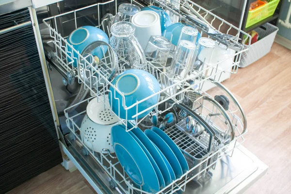 opened Dishwasher after cleaning process both baskets with clean dishes: bowls, glasses, close up