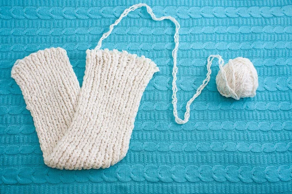 Conceito inacabado. Sinal de vitória. Cachecol branco de malha com uma bola de fio na textura azul de lã de malha. Espaço de cópia. — Fotografia de Stock