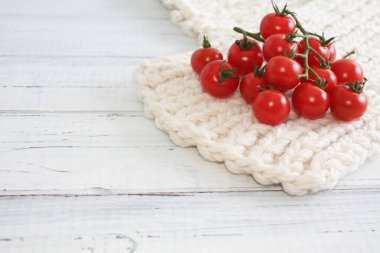 Beyaz yumuşak yüzeyde kırmızı domatesler, ahşap masa arkaplanı. Kışın sebzeler. Uzayı kopyala Seçici odak.