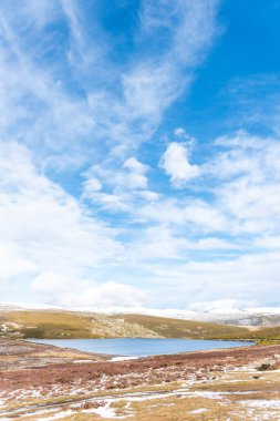 Kışın dağlardaki bir gölün dikey görüntüsü güneşli bir gün manzarası ve temiz ve kirlenmemiş havayı soluyan karlı dağlar.