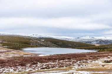 Kışın göl, karlı dağların ortasında güneşli, bulutlu bir günde