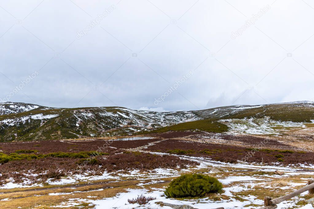 Horizontal image of snowy mountains on a winter day, overcast with grass and high mountain scrub