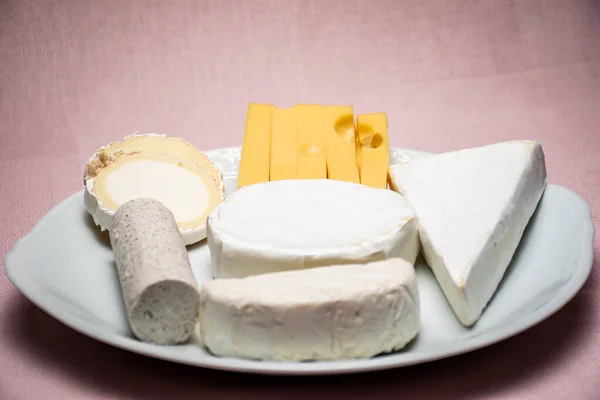 チーズの盛り合わせテーブル ヤギのチーズ牛のチーズ羊のチーズ 森の果物やナッツ 背景はピンクの布で ピントが合わない — ストック写真